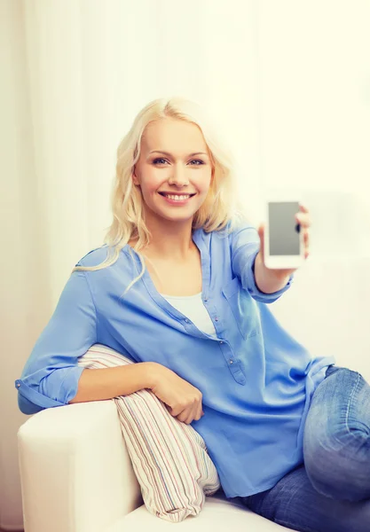 Lachende vrouw met lege smartphone scherm thuis — Stockfoto