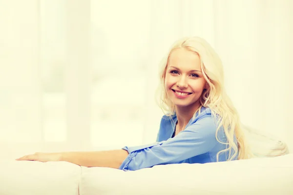 Mujer joven sonriente acostada en el sofá en casa — Foto de Stock
