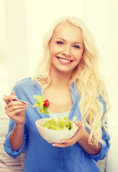 Mujer joven sonriente con ensalada verde en casa —  Fotos de Stock