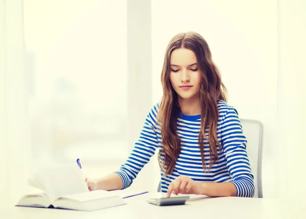 Menina estudante com livro, calculadora e notebook — Fotografia de Stock