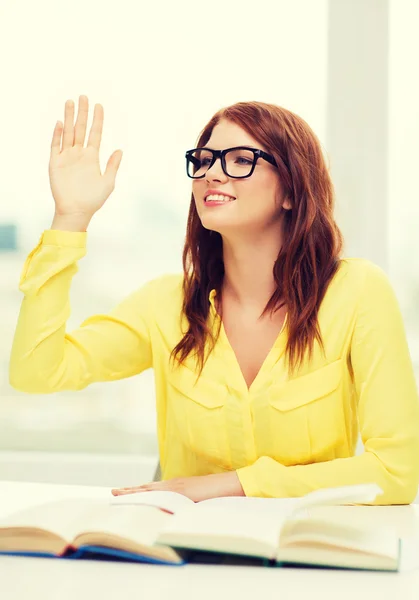 Smiling student girl with books and raised hand — Stock Photo, Image