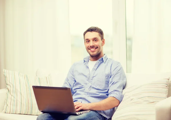 Homme souriant travaillant avec un ordinateur portable à la maison — Photo