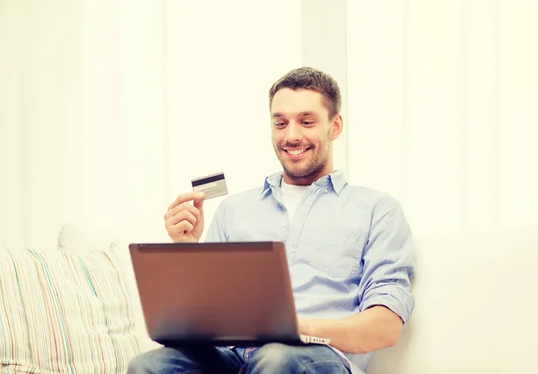 Hombre sonriente trabajando con laptop y tarjeta de crédito — Foto de Stock