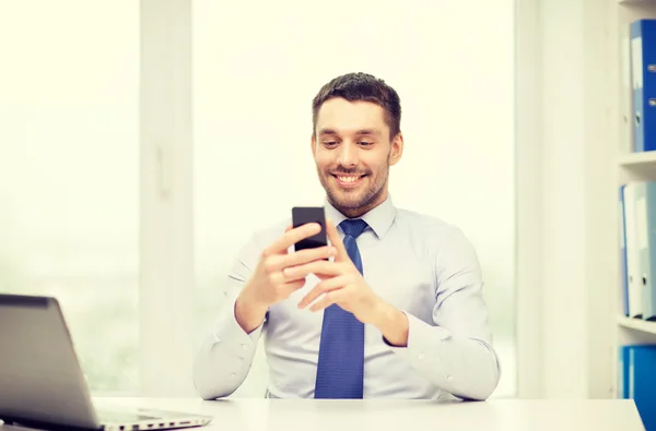 Uomo d'affari con computer portatile e smartphone in ufficio — Foto Stock