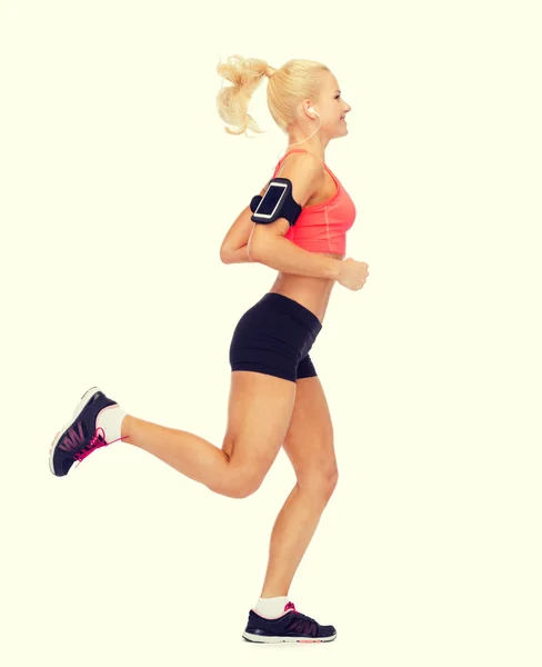 Mujer deportiva corriendo con smartphone y auriculares —  Fotos de Stock