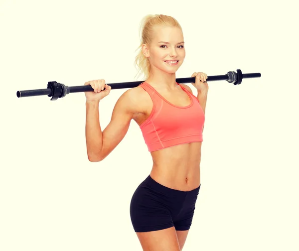 Smiling sporty woman exercising with barbell — Stock Photo, Image