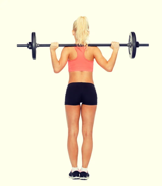 Sporty woman exercising with barbell from the back — Stock Photo, Image