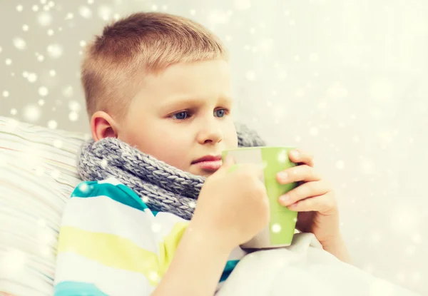 Chory chłopiec z grypy w łóżku pić z kielicha w domu — Zdjęcie stockowe