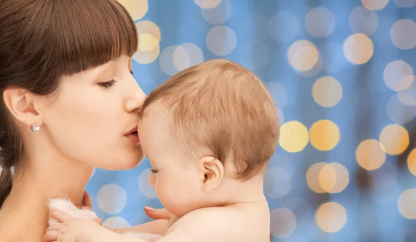 Mãe feliz com bebê sobre luzes fundo — Fotografia de Stock