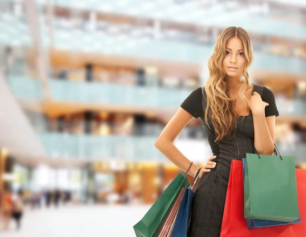 Mujer feliz joven con bolsas de compras en el centro comercial — Foto de Stock