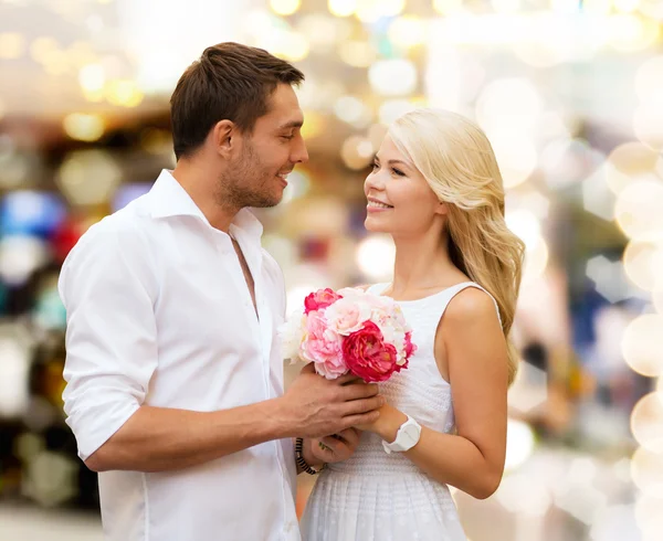 Glückliches Paar mit Blumen über Lichtern Hintergrund — Stockfoto