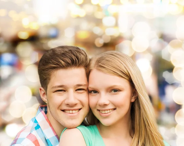 Couple souriant étreignant sur fond de lumières — Photo