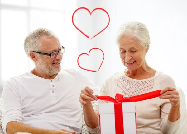 Happy senior couple with gift box at home — Stock Photo, Image