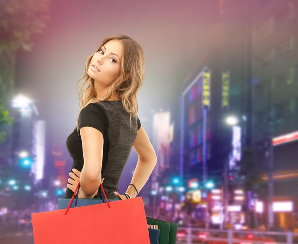 Jonge gelukkig vrouw met boodschappentassen over stad Stockafbeelding