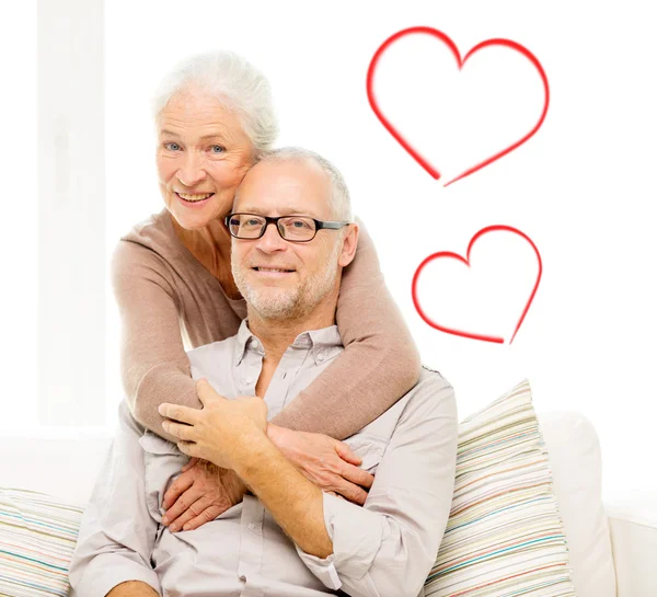 Happy senior couple hugging on sofa at home — Stock Photo, Image