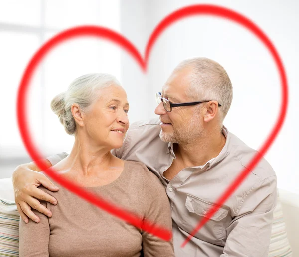 Happy senior couple hugging on sofa at home — Stock Photo, Image