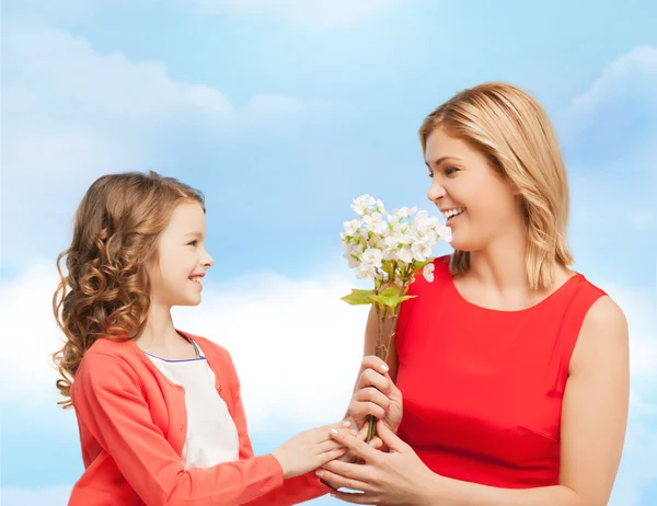Happy little daughter giving flowers to her mother — Stock Photo, Image