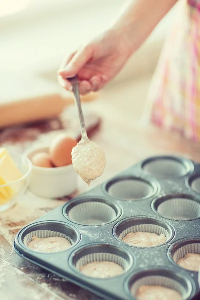 Close up of hand filling muffins molds with dough — Stock Photo, Image