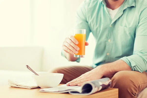 Close up of man with magazine drinking juice — Stock Photo, Image