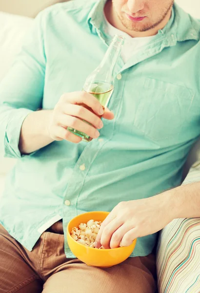 Primer plano del hombre con palomitas de maíz y cerveza en casa — Foto de Stock