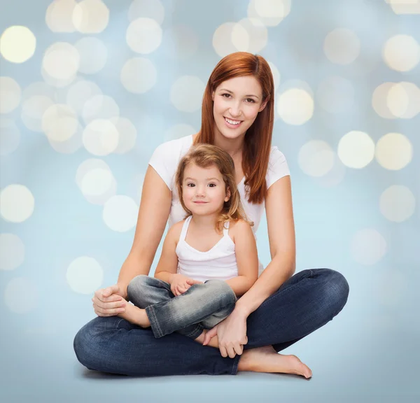 Gelukkig moeder met kleine meisje over vakantie lichten — Stockfoto