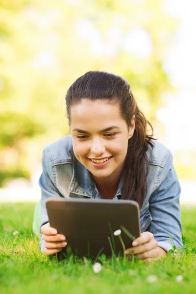 Sorridente menina tablet pc deitado na grama — Fotografia de Stock