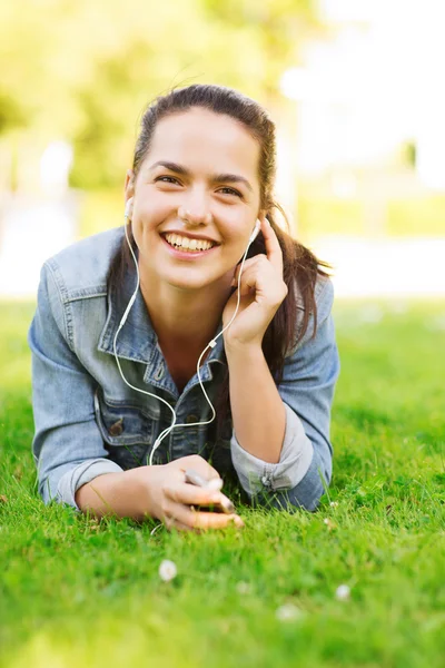 Niña sonriente con teléfono inteligente y auriculares — Foto de Stock