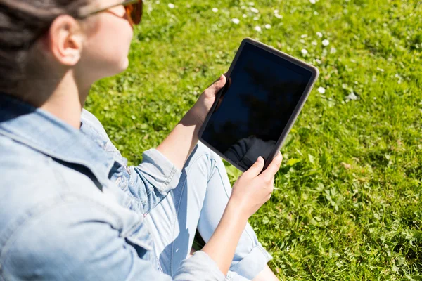 Primer plano de la chica con la tableta de la PC sentado en la hierba —  Fotos de Stock