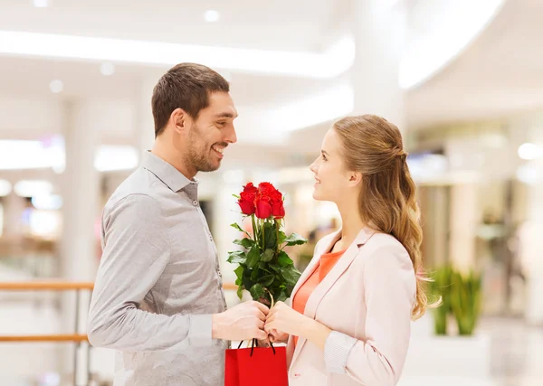 Felice giovane coppia con fiori nel centro commerciale — Foto Stock