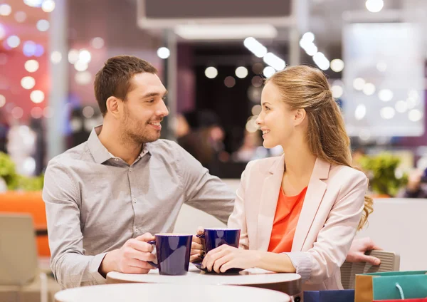 Gelukkige paar met boodschappentassen drinken koffie — Stockfoto