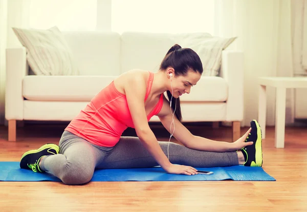 Usmíval se dospívající dívka streching na podlaze doma — Stock fotografie