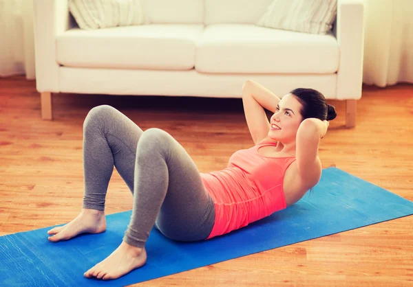 Smiling girl doing exercise on floor at home — Stock Photo, Image