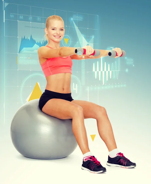 Woman with dumbbells sitting on fitness ball — Stock Photo, Image