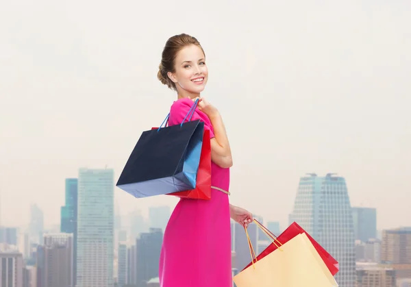 Jonge gelukkig vrouw met boodschappentassen over stad — Stockfoto