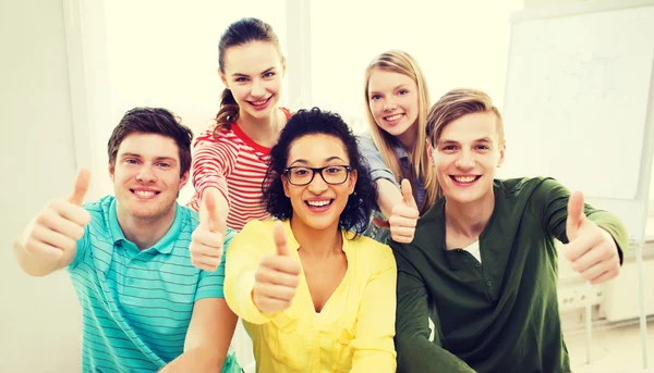 Estudiantes sonrientes en la escuela mostrando pulgares hacia arriba Imagen De Stock