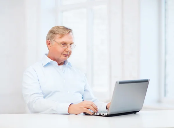 Old man in eyeglasses working with laptop at home — Stock Photo, Image