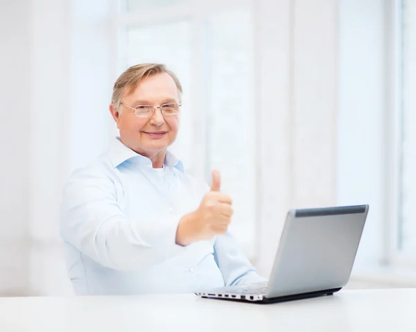 Starý muž s přenosným počítačem ukazuje palec — Stock fotografie