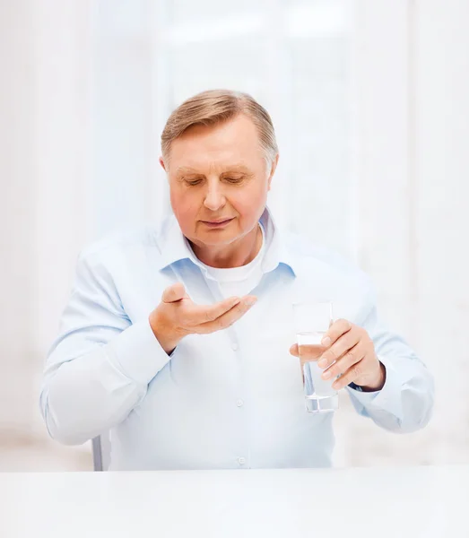 Homem velho com pílulas ang vidro de água — Fotografia de Stock