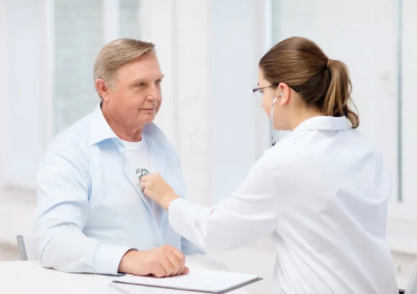 Doctora con anciano escuchando latidos cardíacos — Foto de Stock