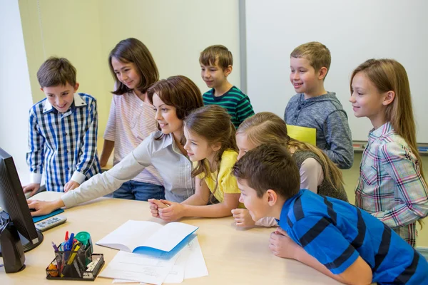 Groep van jonge geitjes met leraar en computer op school — Stockfoto