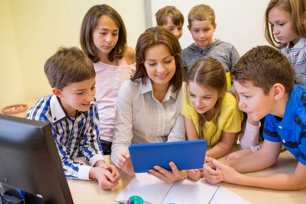 Groep van jonge geitjes met leraar en tablet pc op school — Stockfoto