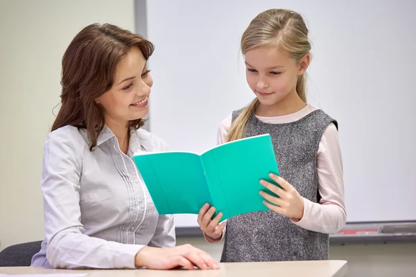 Skolflicka med anteckningsbok och lärare i klassrummet — Stockfoto