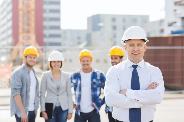 Groep van lachende bouwers in hardhats in openlucht — Stockfoto