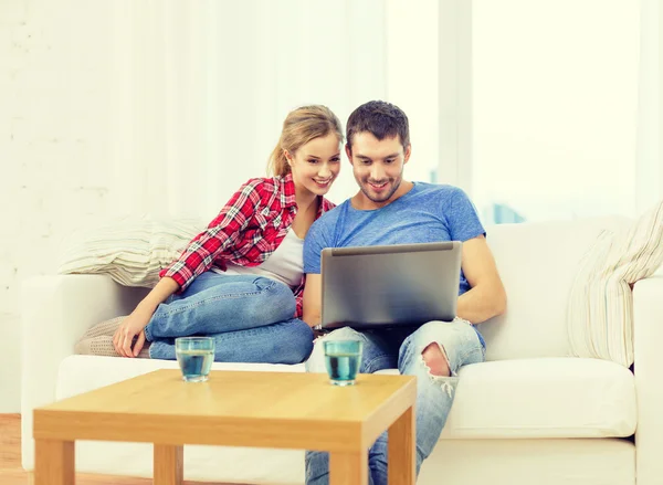 Улыбающаяся пара с ноутбуком дома — стоковое фото