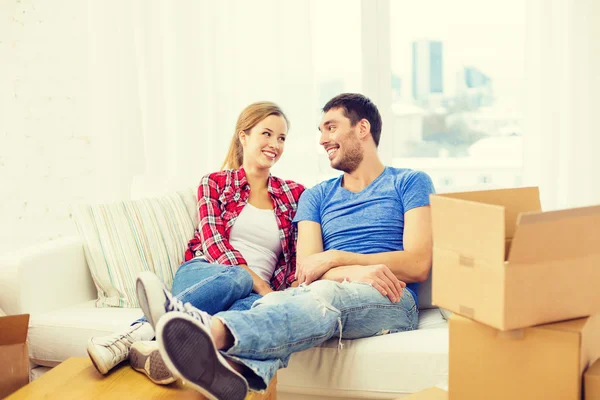 Pareja sonriente relajándose en un sofá en un nuevo hogar — Foto de Stock