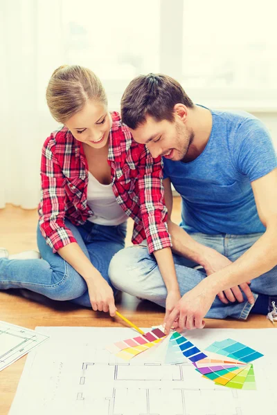 Coppia sorridente che guarda i campioni di colore a casa — Foto Stock