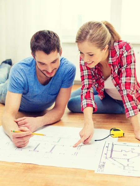 Smiling couple looking at blueprint at home — Stock Photo, Image