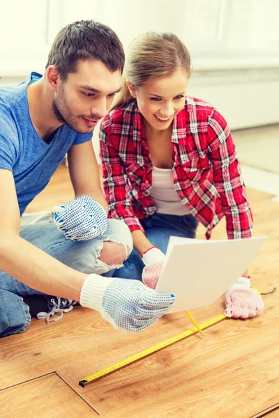 Smiling couple measuring wood flooring — Stock Photo, Image