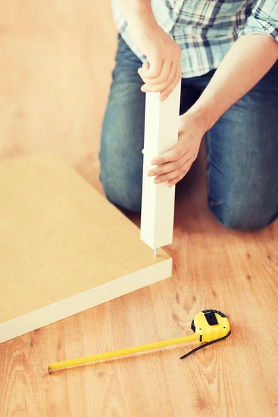 Close up of male hands assemblying legs to table — Stock Photo, Image