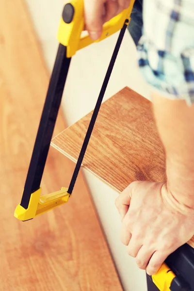 Close up de mãos masculinas corte de placa de piso de parquet — Fotografia de Stock